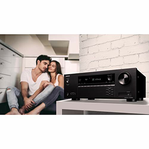 Couple sitting in a room with a home audio receiver on a table.